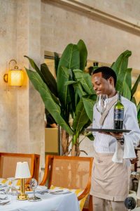 Professional waiter elegantly serving red wine to guests at La Terrasse Diani Beach